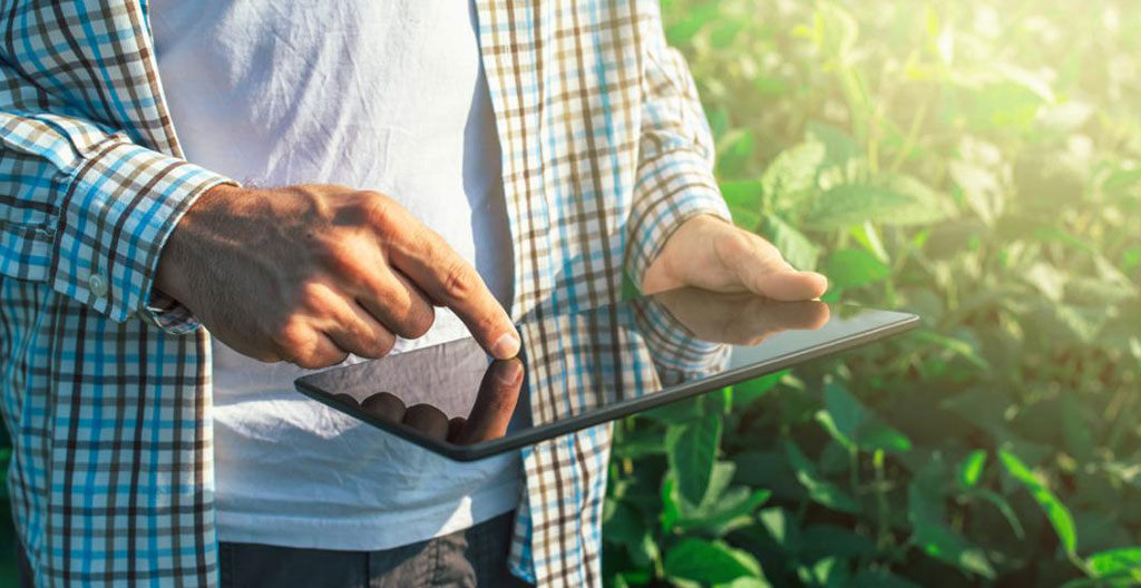 Agriculteur analysant une carte parcellaire colorée sur un ordinateur portable posé sur une table dans une exploitation agricole